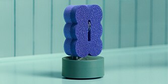 Estropajo morado Brite de Scotch-Brite™ en un soporte para estropajos junto al fregadero.
